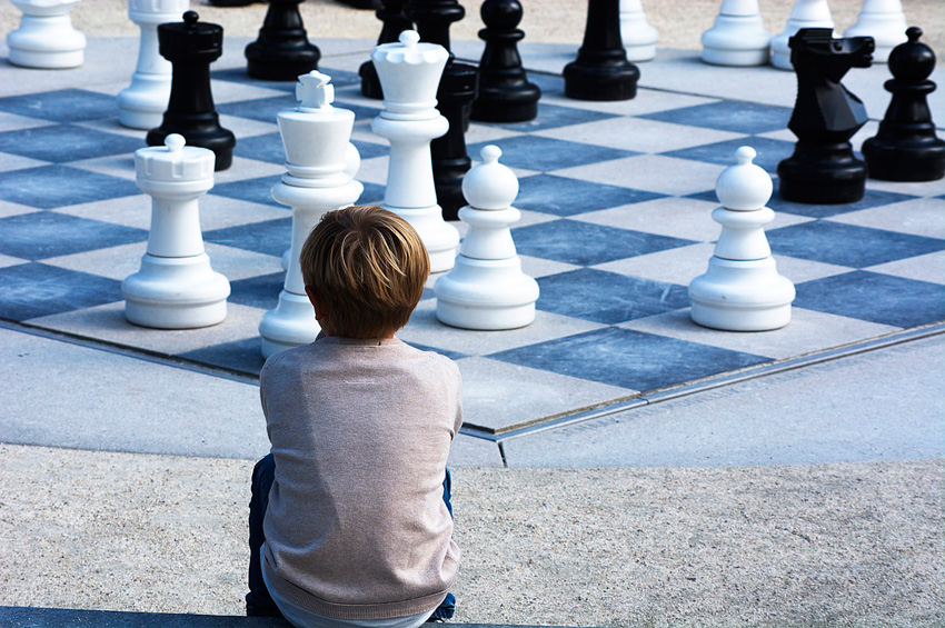 Niño mirando un tablero gigante de ajedrez